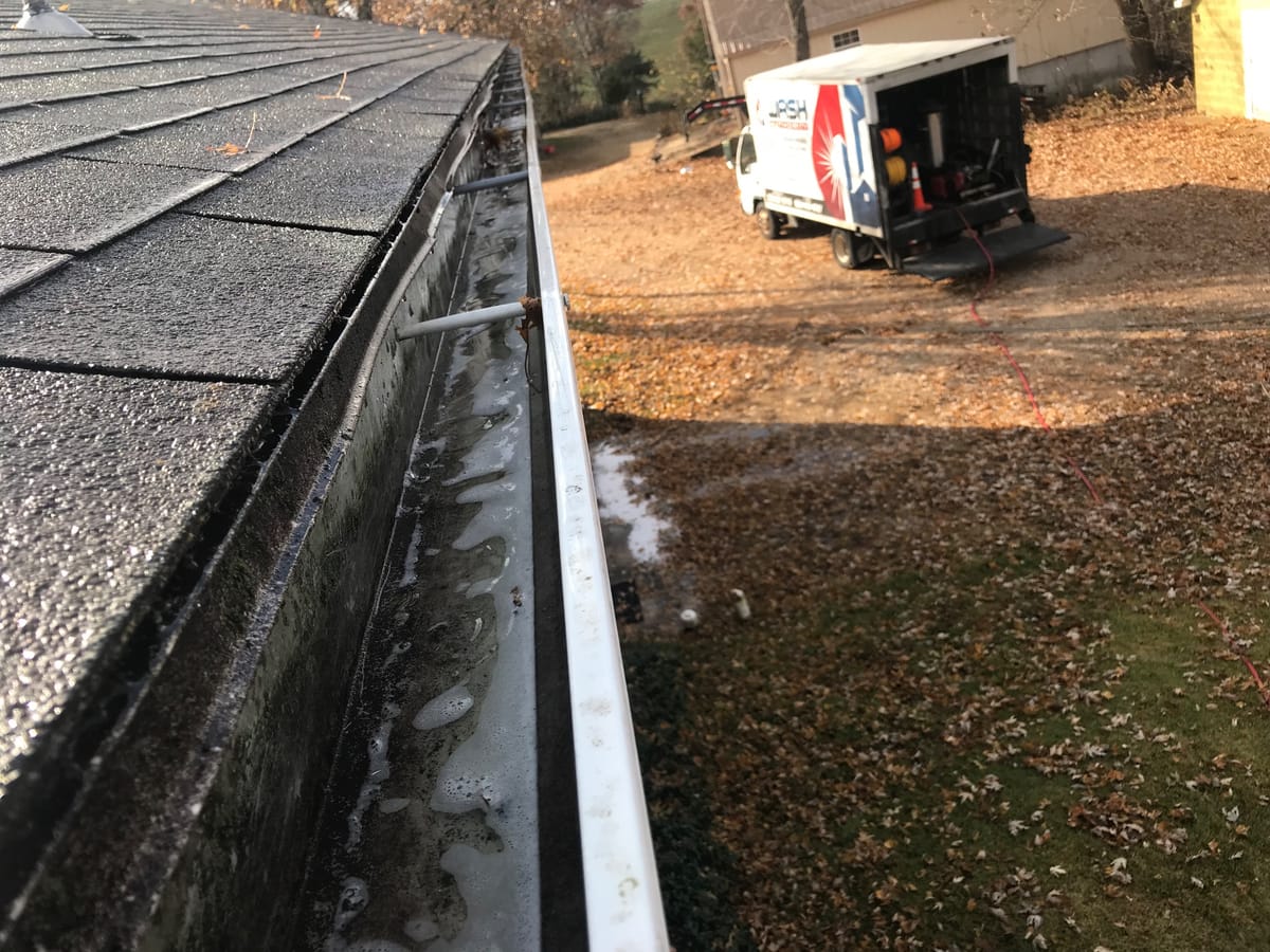 The same gutter run after cleaning, empty and rinsed, Wash Authority truck in the driveway
